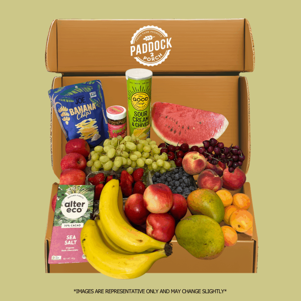 The Christmas Fruit & Pantry Hamper- Small includes a box of assorted fresh fruits, banana chips, chocolate, dip, and sour cream & chive chips, all labeled “Paddock to Porch.”.